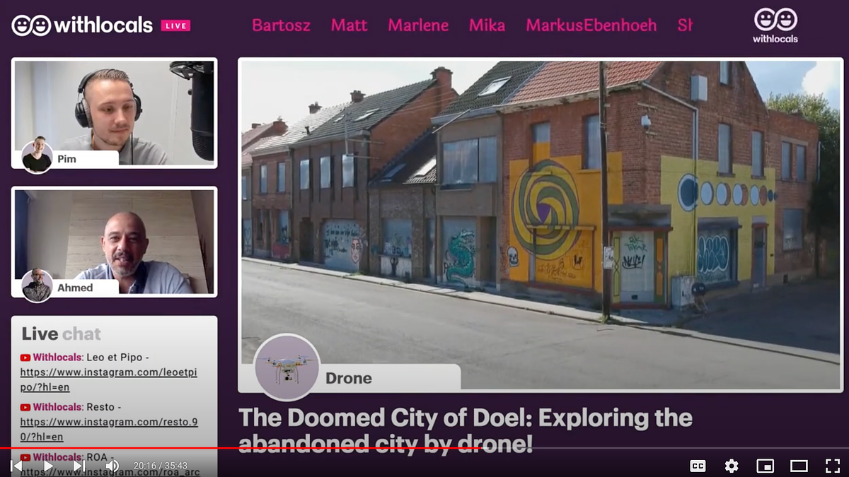 A screenshot of an online experience that shows (in the main screen) a picture of a building with colourful drawings. On the side of the main screen, there are 2 separate windows, one with a moderator and another with the presenter. on the left bottom side of the screen there is a live chat box