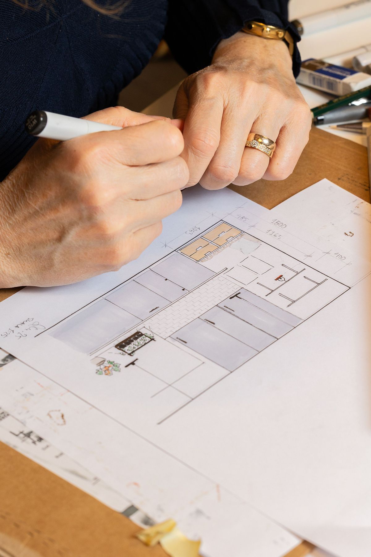 N&auml;rbild av h&auml;nder som skissar en planritning vid bord &ndash; inredningsdesign i process.