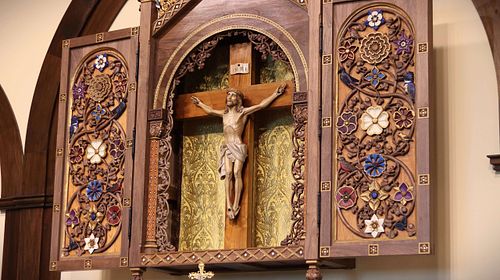 Closeup view of the altarpiece covered with hand-carved vines, flowers, and birds.