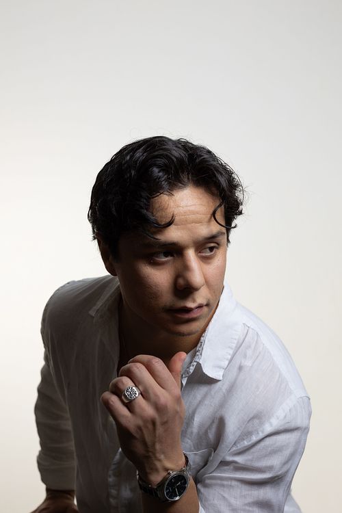 Man i vit skjorta lutar lätt framåt och ser åt sidan, ring och armbandsur synliga, ljus studiebakgrund i Stockholm