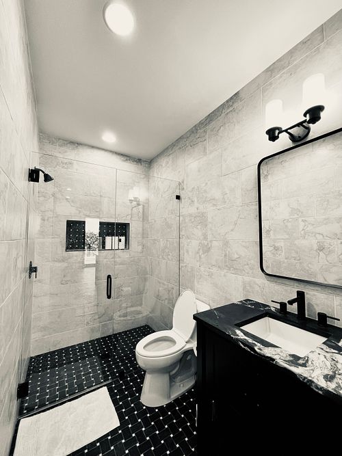 Man Cave bathroom, dark colors, floor to ceiling tile, glass shower wall