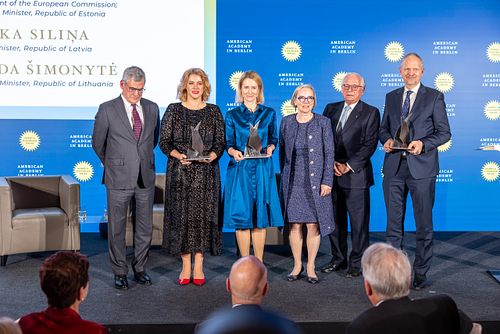 Six people standing on stage during a gala dinner at the Axica Convention Centre in Berlin.