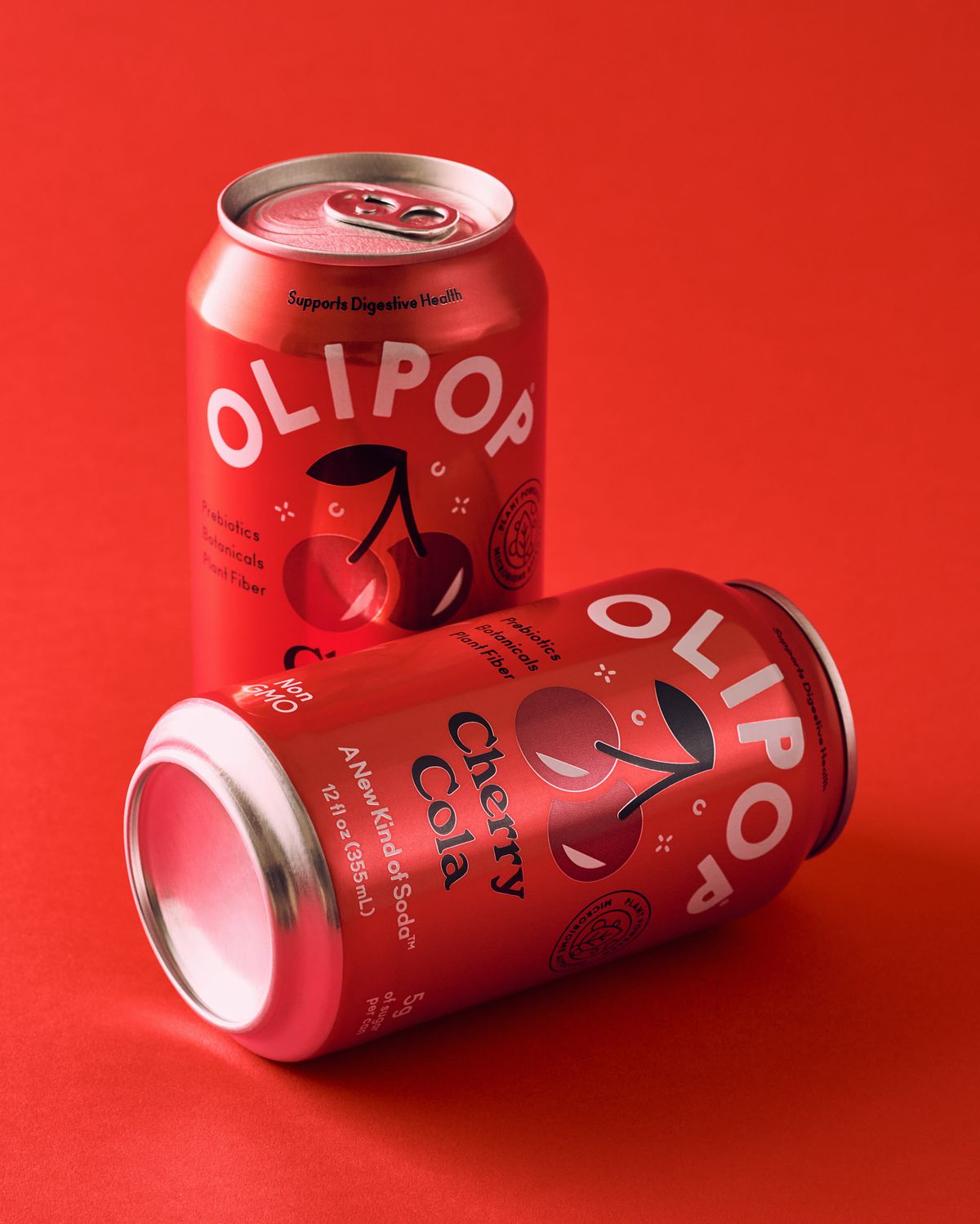 Two red cherry cola cans on a red background.