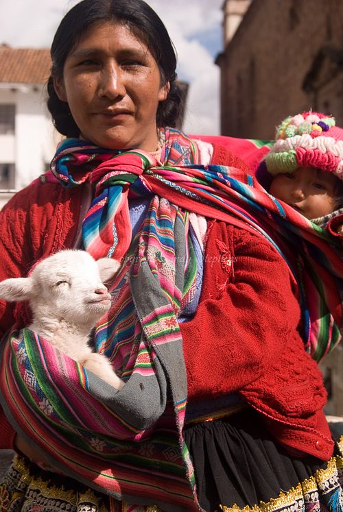 Peruvian woman in traditional clothing holding a lamb and baby