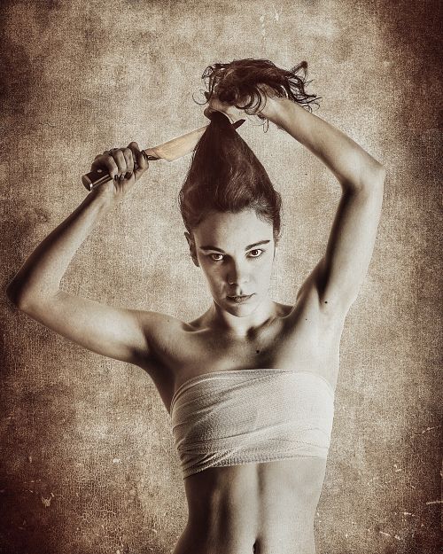 Portrait d'une femme compressant sa poitrine et se coupant les cheveux avec un couteau, exprimant la lutte identitaire et la dualit&eacute; de genre &mdash; photographie fine art par Pascal Yennis, Namur, Belgique.