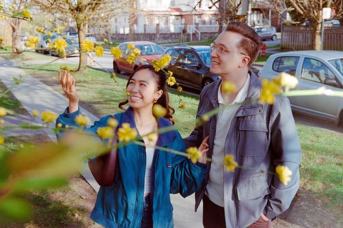 a 35mm film shot of a couple stopping to look at some flowers on a tree