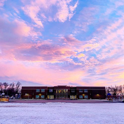 A building under a massive blue and pink sky of clouds