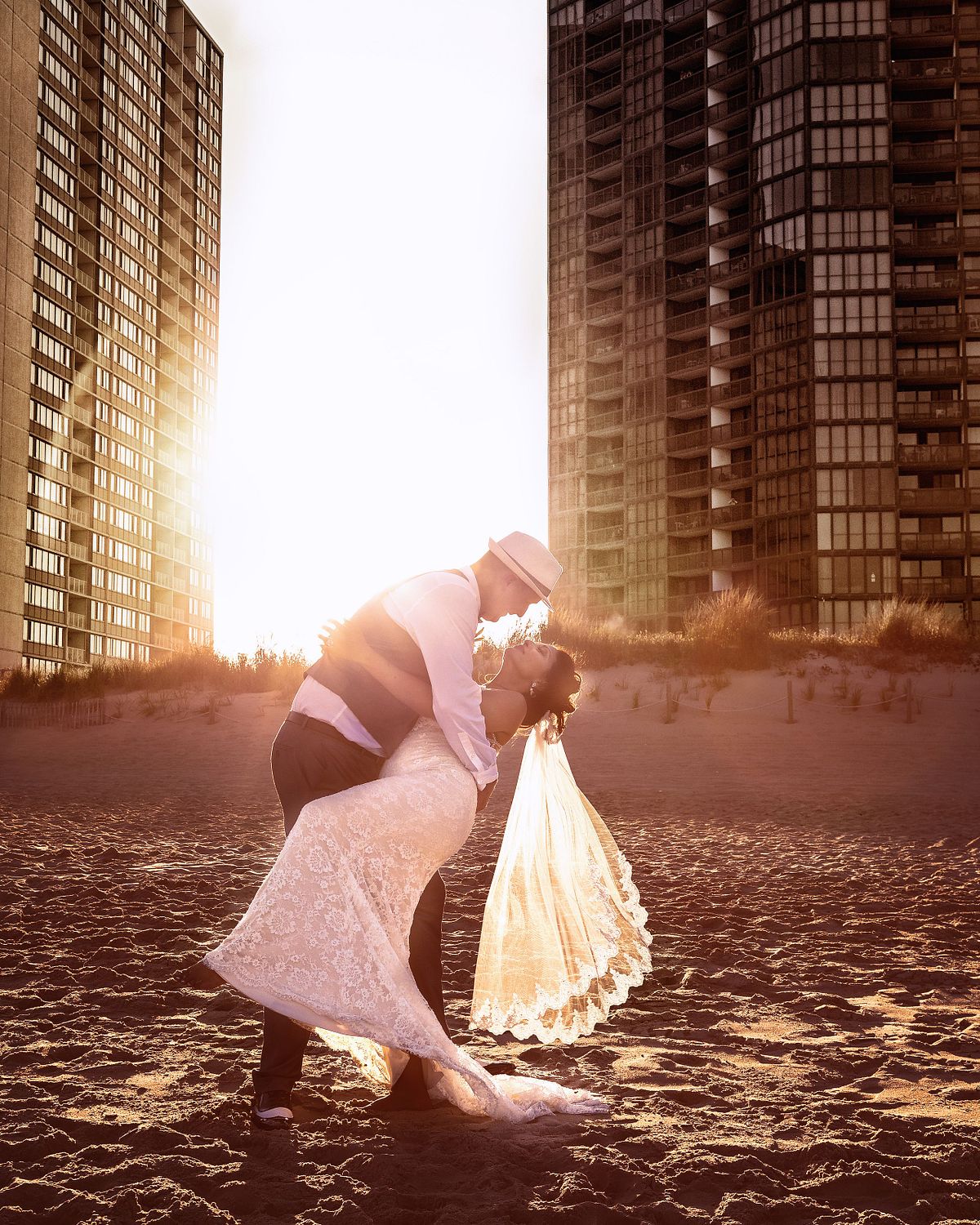 groom dipping his bride during sunset hours at the beach near Golden Sands, Ocean city, the veil is hanging down al most touching the sand