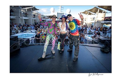 Horizontal color image of Randy Hansen with band members posing on an outdoor ship deck stage before a large crowd