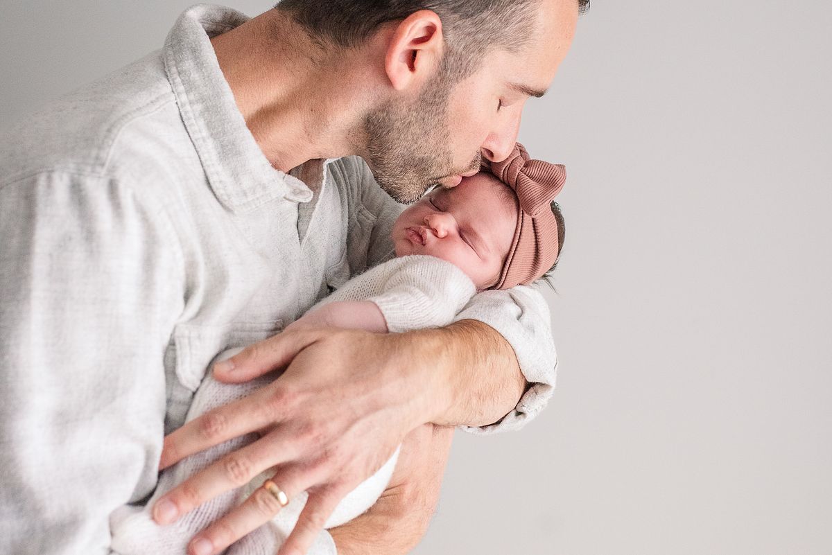 dad holding and kissing his newborn baby girl near window light with cranberry township, pa newborn photographer