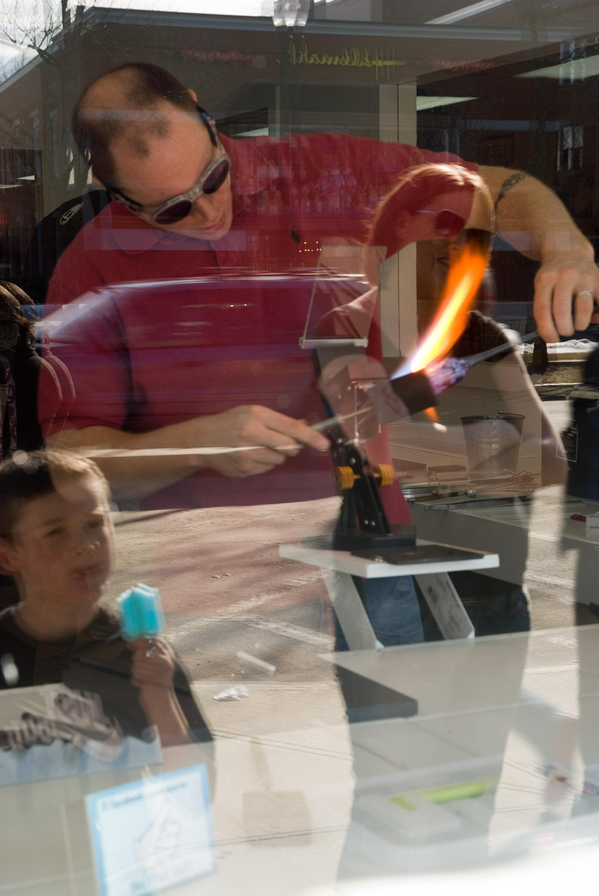 Mother and child eating cone in front of American main street store watching glass blower inside