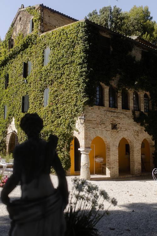 Gli sposi camminano davanti alla facciata in pietra della Badia ricoperta di verde.