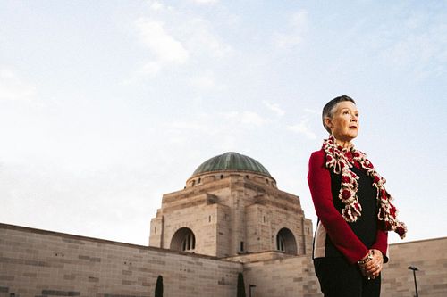 Woman Karen Bird stands out the front of the Australian War Memorial wearing a red top.