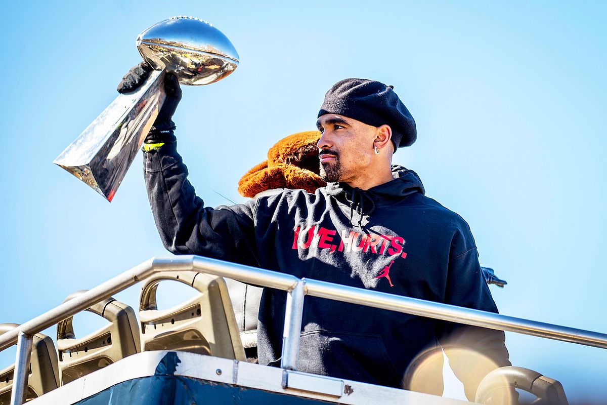 Editorial event photography of Philadelphia Eagles quarterback Jalen Hurts raising the Vince Lombardi Trophy during the city&rsquo;s championship parade, symbolizing leadership, pride, and legacy.