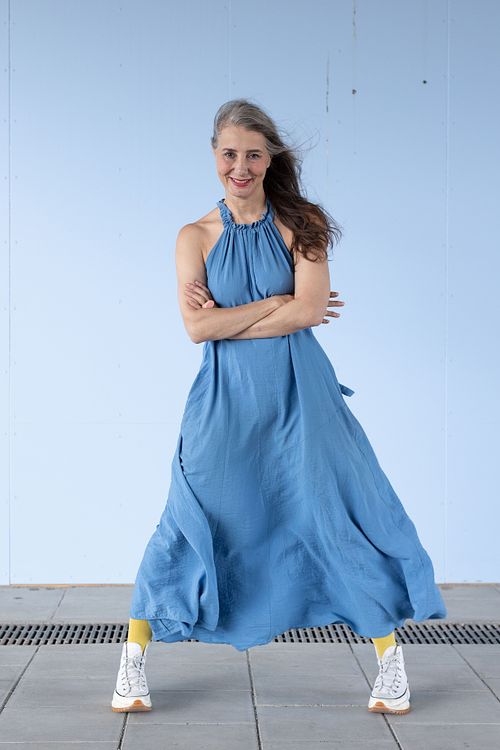 Helkroppsporträtt för personal branding i Stockholm – person i blå klänning mot ljusblå vägg.