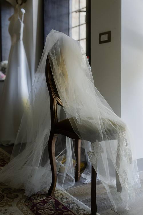 Abito da sposa appeso vicino alla finestra con luce naturale sulle stoffe.