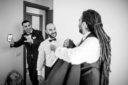 "bianco e nero invitati che raggiungono lo sposo che si veste"