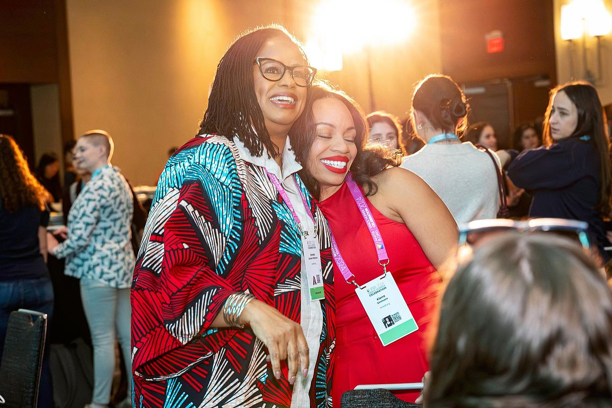 Corporate event photography capturing a warm embrace during a networking mixer at the Grace Hopper Celebration 2024 in Philadelphia, highlighting authenticity, community, and connection within the tech industry.