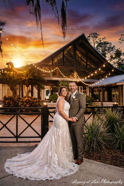 A bride and groom embracing at sunset in front of the tropical thatched-roof pavilion and palm trees at Paradise Cove in Orlando.