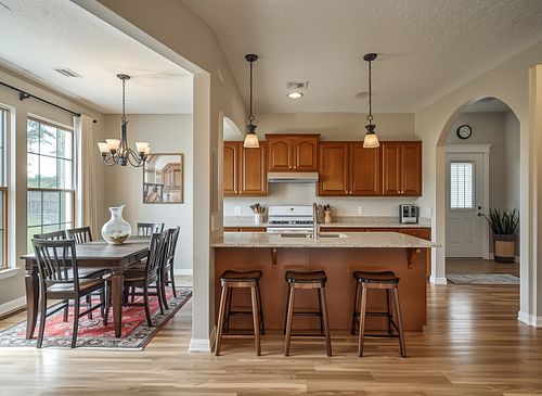 Professional real estate photography of a modern kitchen with wood cabinets, breakfast bar, and adjacent dining room in Gainesville FL by PrimePropertyPhoto.