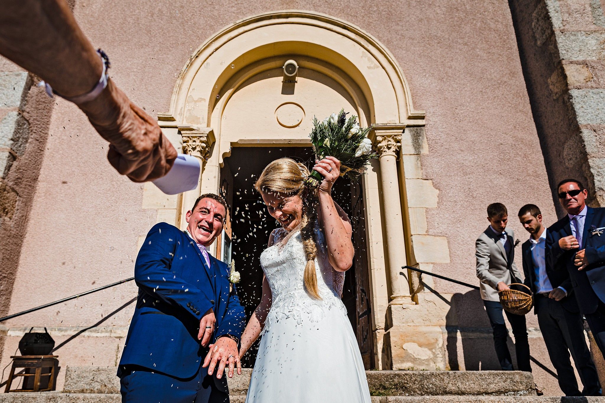 Couple de mari&eacute;s &agrave; la sortie de l'&eacute;glise &agrave; qui on jette traditionnellement du riz captur&eacute; par S&eacute;bastien CLAVEL photographe de Mariage &agrave; Lyon et Gen&egrave;ve