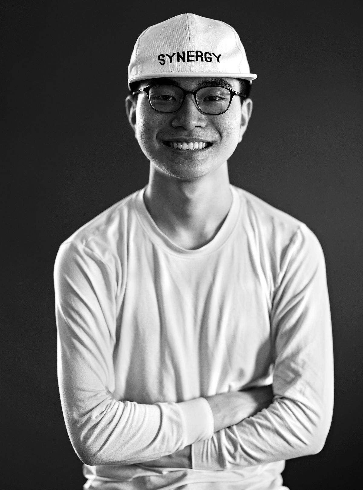 Corporate portrait of a Japanese Man wearing all white against a dark grey background.