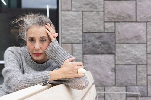 Miljöporträtt för personal branding – person i grå tröja mot stenmur med fokuserat uttryck.