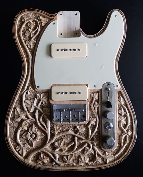 hand-carved guitar in the gothic style with flowing vines and flowers