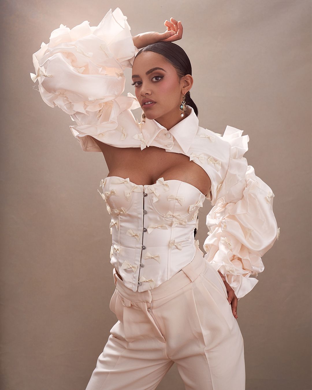 Fashion editorial portrait of a woman wearing a white corset, white dress bands, and exaggerated white puffy sleeves