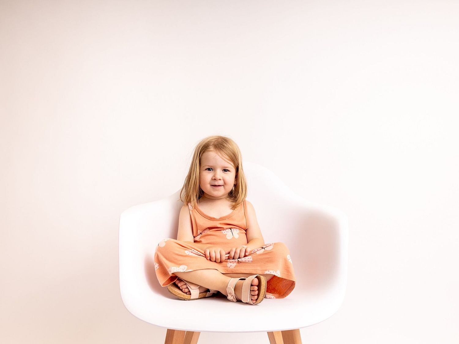 Monthly growth photo on a chair taken by Basel photographer capturing white little girl's cute smile