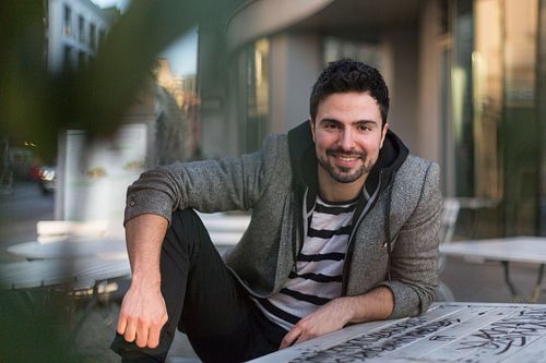 Toni Gojanovic in a gray jacket and striped sitting at the table.