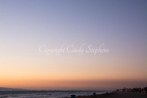 Pink and purple hues with colored lights along the California coastline