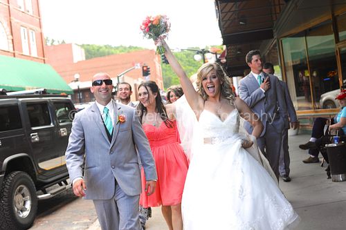 Bride lifts her bouquet in the air as her wedding party walks behind her