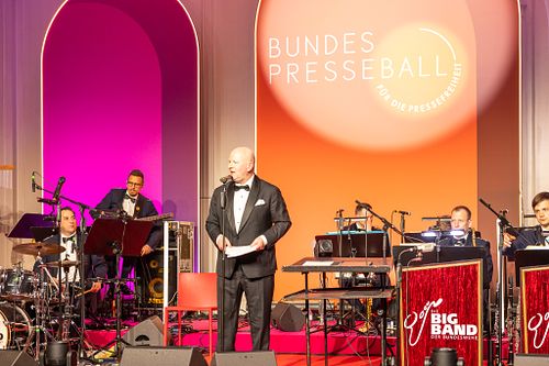 Mathis Feldhoff addressing the audience with live orchestra at the Bundespresseball 2024 gala event.