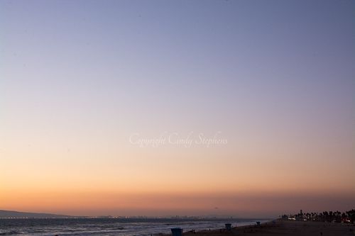 Pink and purple hues with colored lights along the California coastline