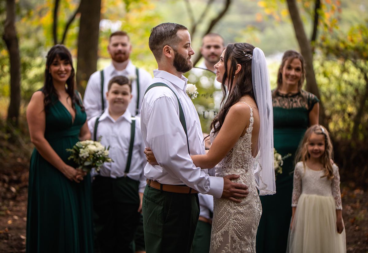 bride and groom posing in front of the wedding party after the ceremony in the forest