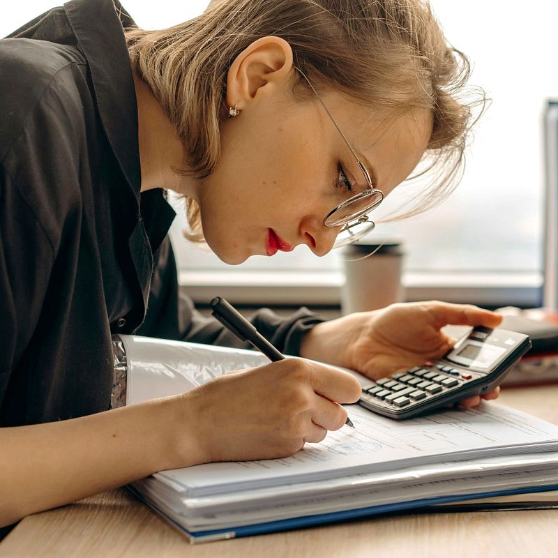 Menopausal woman using calculator while taking notes