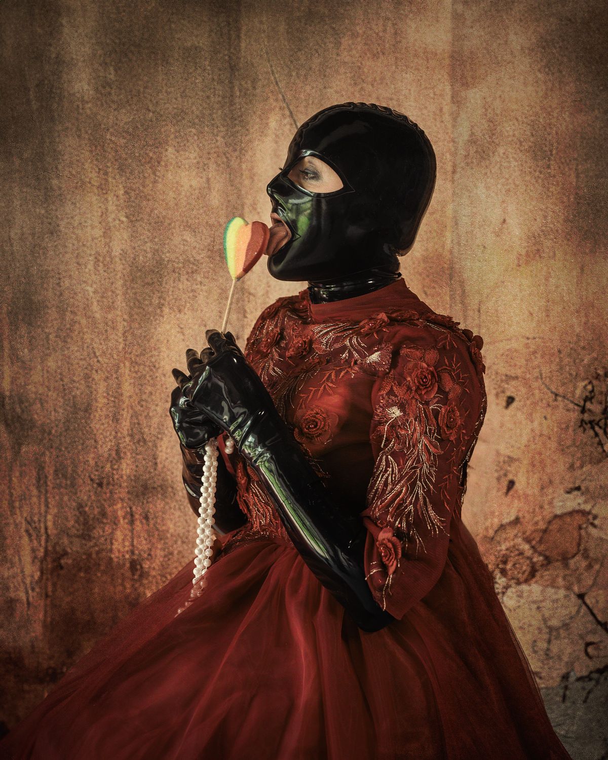 femme en robe rouge de princesse et tenue latex, l&eacute;chant une sucette, regard provocateur, ambiance d&eacute;cal&eacute;e et baroque, photographie fine art
