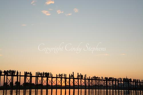 Figures strolling across a wooden bridge at sunset in Inle Lake