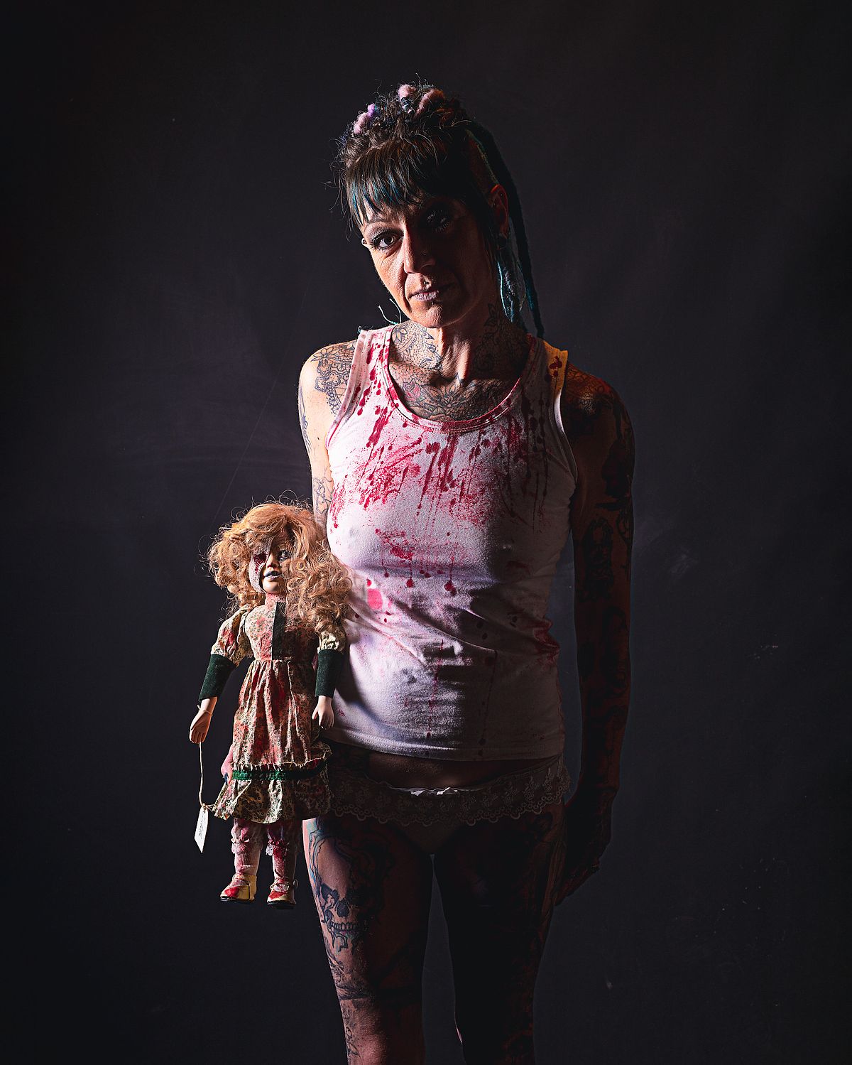 photo tarot La Psychopathe, femme sombre avec poup&eacute;e d&eacute;labr&eacute;e, sourire m&eacute;lancolique dans une ambiance lunaire