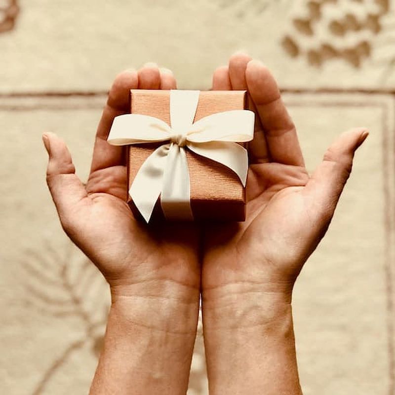 small box with bow held by two outstretched hands