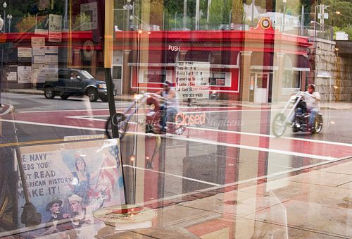 Reflection of motorcycle riders in a shop window with a vintage Navy Needs You poster