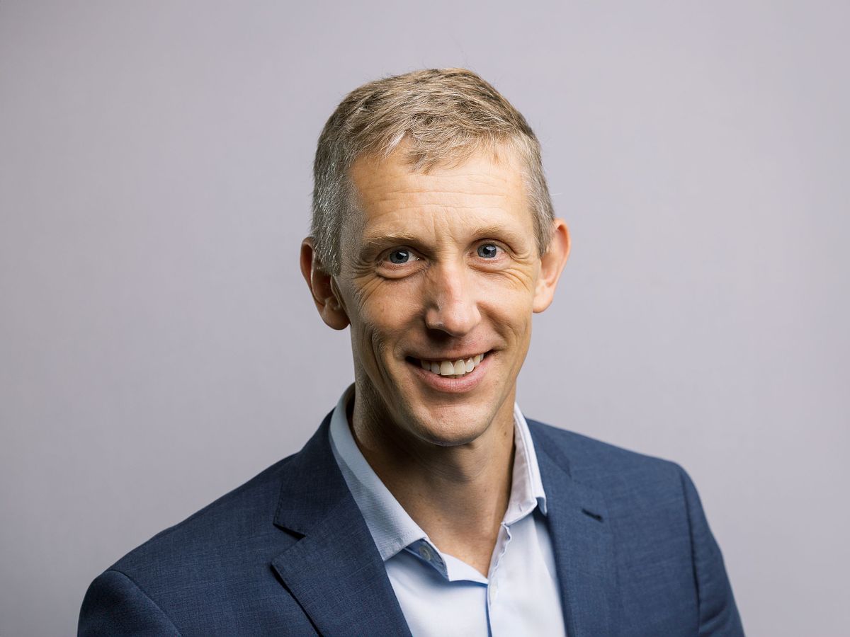 A close-up headshot of a man against a white backdrop shot in a studio in Carrboro, NC