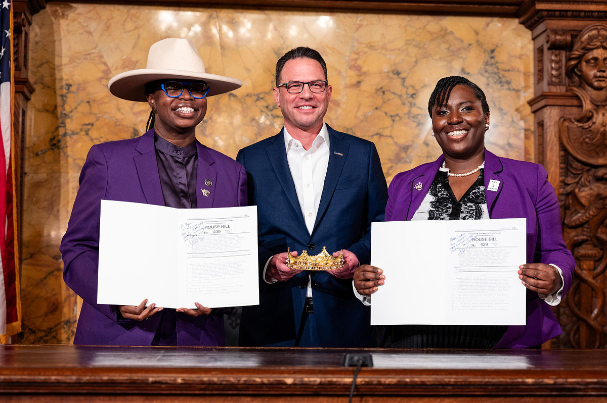 Governor Josh Shapiro stands with CROWN Act advocates holding signed legislation during the Pennsylvania bill signing ceremony