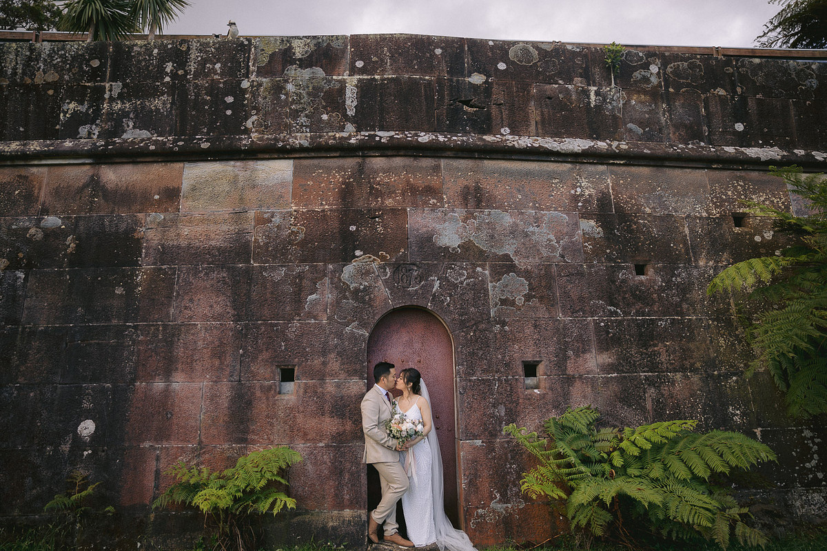 Romantic bridal portraits of a bride and groom sharing a kiss in front of the fort at Harbour View Lawn