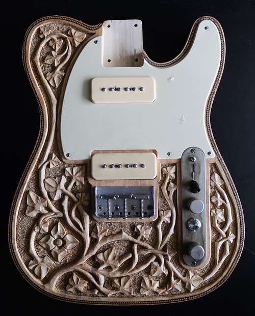 hand-carved guitar in the gothic style with flowing vines and flowers
