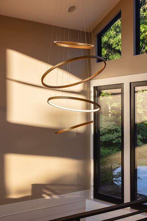 Satin brass chandelier, suspended rings, over stair