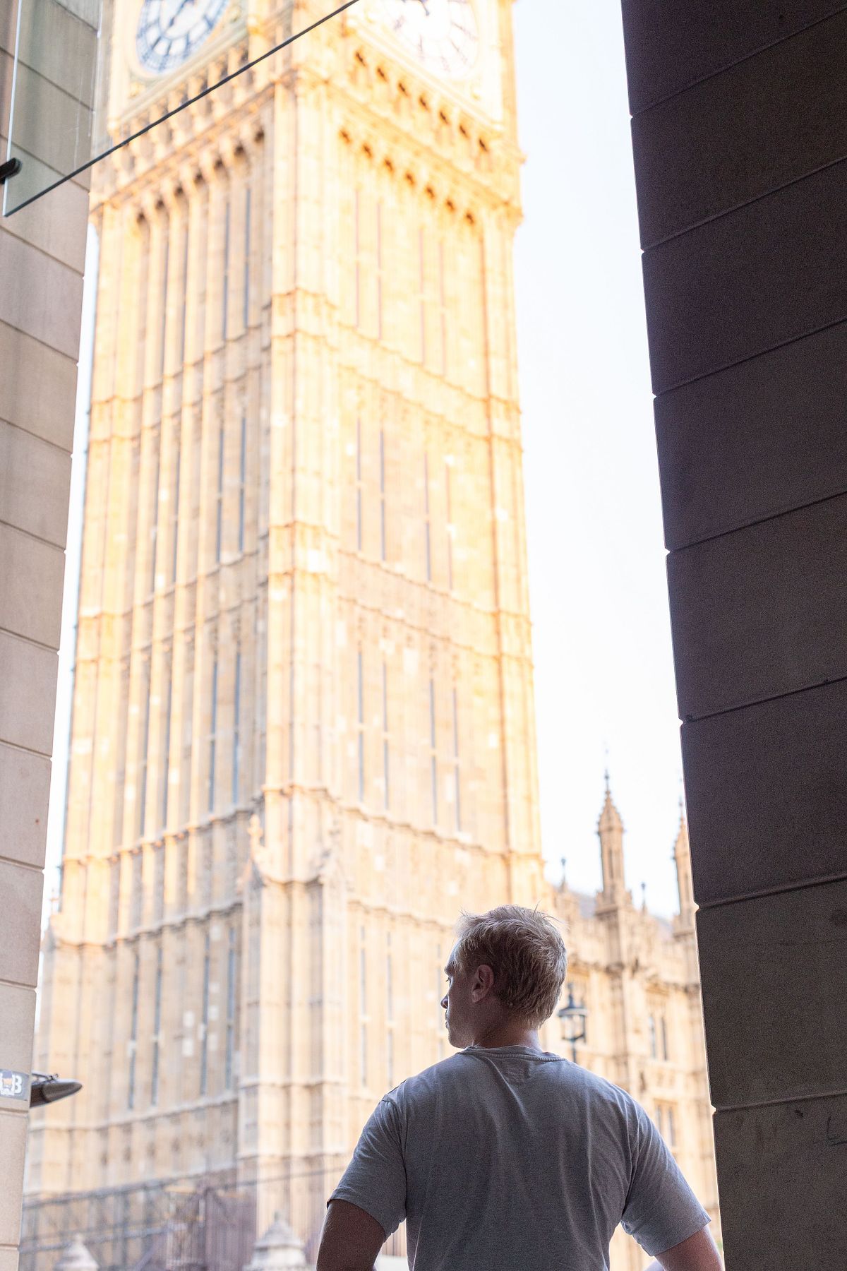 Milj&ouml;portr&auml;tt av en man i silhuett som st&aring;r i en port&ouml;ppning och ser mot Big Ben i London, mjukt kv&auml;llsljus.