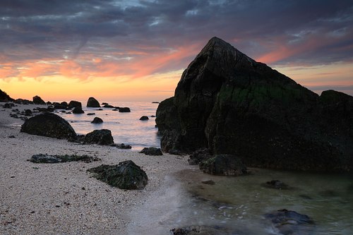 Color sunset clouds over rocky coastline.