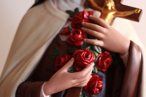 Close up photo of the roses and crucifix that identify the statue as one of St. Therese